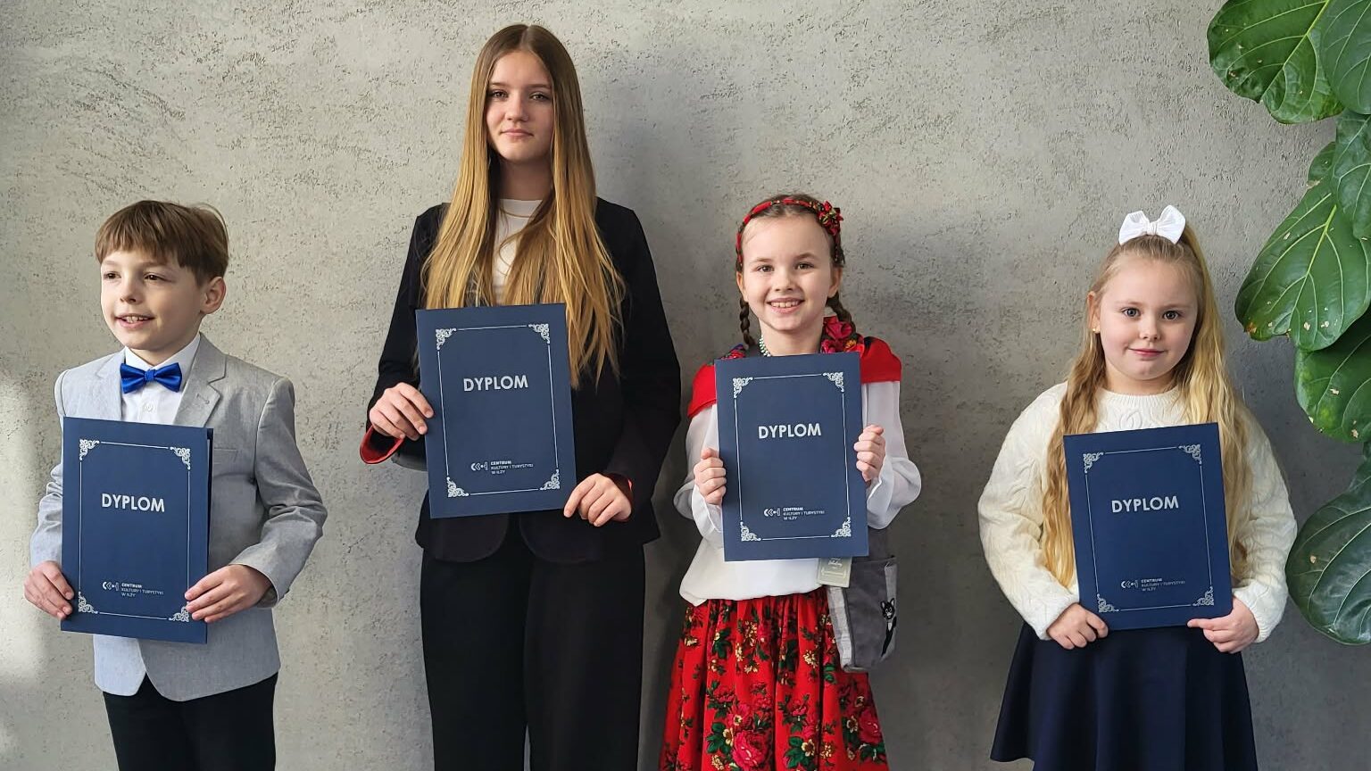 Czworo uczestników konkursu recytatorskiego pozuje do zdjęcia z dyplomami.